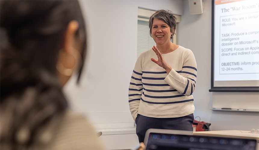 Professor Aimee Christian speaks to students in a classroom, with a presentation slide projected behind her.
