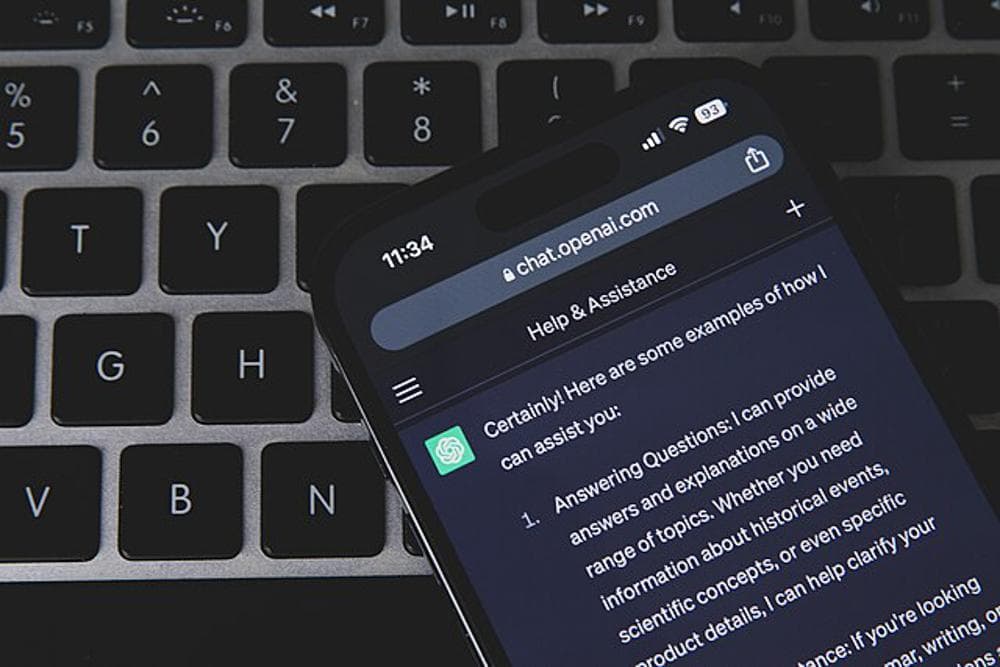 A phone showing ChatGPT resting on a laptop keyboard